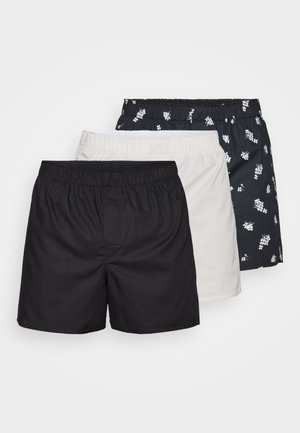Set of three pairs of shorts: one black, one white, and one patterned navy with white flowers, all with elastic waistbands and lightweight fabric.