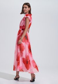 Rózsaszín, virágmintás, fodros ujjú ruha, nagy piros és fekete virágmintákkal. Áttetsző anyag elegánsan omlik bokáig.