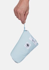 Hand hält eine hellblaue Mammut-Tasche am Reißverschluss gegen einen schlichten weißen Hintergrund.