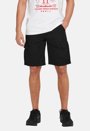 Black cargo shorts made of cotton, featuring side pockets and a relaxed fit. Worn with a white graphic t-shirt and black athletic shoes.