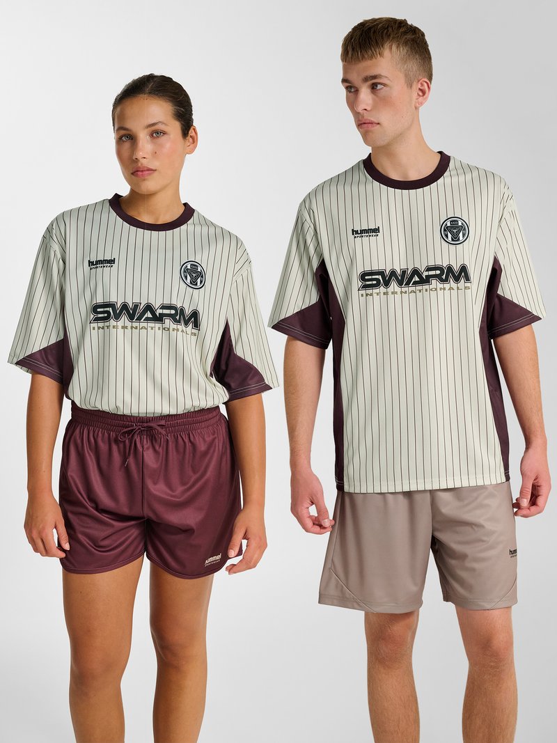 Dwa modele w pasiastych beżowych i bordowych koszulkach sportowych z logo „SWARM”, zestawione z bordowymi i beżowymi szortami, stojący na jednolitym tle.