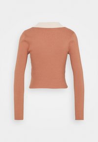 Camisola de mangas longas em tecido canelado, na cor terracota suave, com um colarinho beige em contraste e um design justo na cintura.