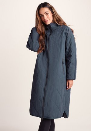 Quilted long coat in dark teal, featuring a high collar, front zipper, and side pockets. Smooth texture with diamond pattern.