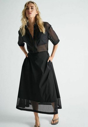 Zwart outfit met een doorschijnende, korte mouwen, knoopjesbroek top en een lange rok met een mesh zoom, gemaakt van lichte materialen.