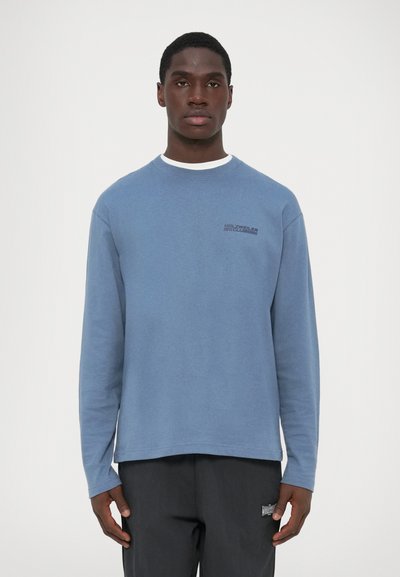 Chemise à manches longues bleu en mélange de coton, avec un col ras du cou et un petit logo sur la poitrine. Texture douce, coupe décontractée, ourlet droit.