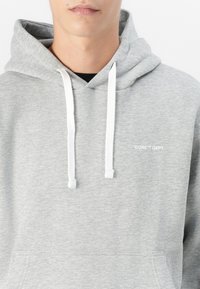 Sudadera gris con textura suave, con cordones blancos y un bolsillo frontal. Texto "CORE™ DEPT." en blanco en el área izquierda del pecho.