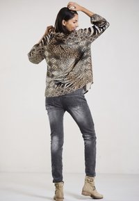 Animal print shirt with geometric patterns, gray jeans, and beige ankle boots. The shirt features a loose fit and long sleeves.