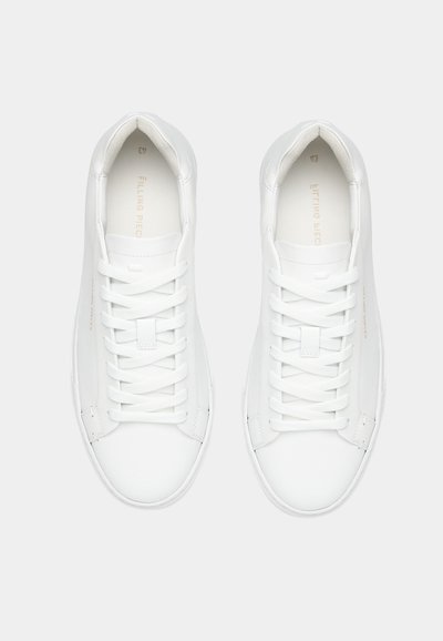 Ζευγάρι άσπρα sneakers χαμηλού προφίλ με λευκά κορδόνια, από πάνω σε απλό ανοιχτό φόντο.