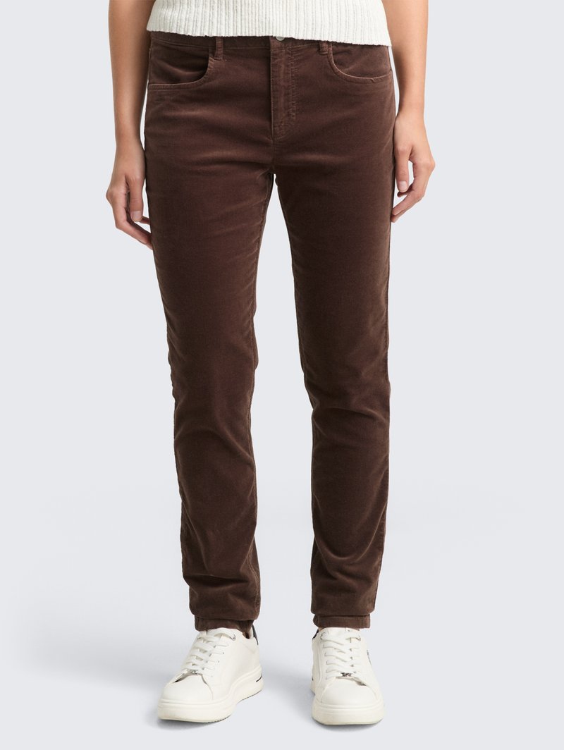 Pantalones de pana marrones con un ajuste slim, que presentan bolsillos frontales y una textura suave. Combinados con zapatillas blancas para un look completo.