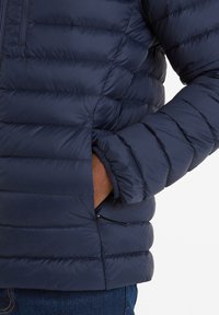 Navy blue puffer jacket with horizontal quilted design, zippered pocket, elasticized cuffs, and smooth, shiny texture.