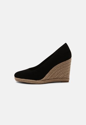 Chaussure à semelle compensée en suède noir avec un bout arrondi et un talon en jute tissé texturé. Le talon mesure environ 3 pouces de haut.