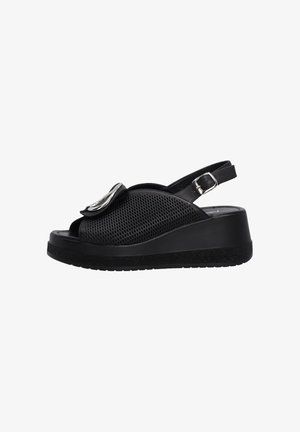 Zwarte open teen sandalen met een geperforeerde bovenkant, verstelbare enkelband en een glanzend metallic accent aan de voorkant. Wigzool.