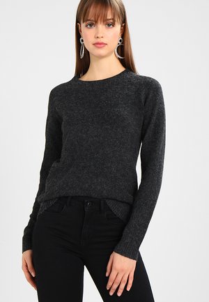 Mørk grå genser laget av myk, strukturert stoff med rund hals og lange ermer, kombinert med mørke jeans for et sammenhengende utseende.