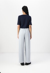 Ναυτικό κοντομάνικο τοπ συνδυασμένο με ανοιχτό γκρι παντελόνι φαρδιάς γραμμής με ελαστική μέση. Το σύνολο ολοκληρώνεται με μαύρες χοντρές γόβες.