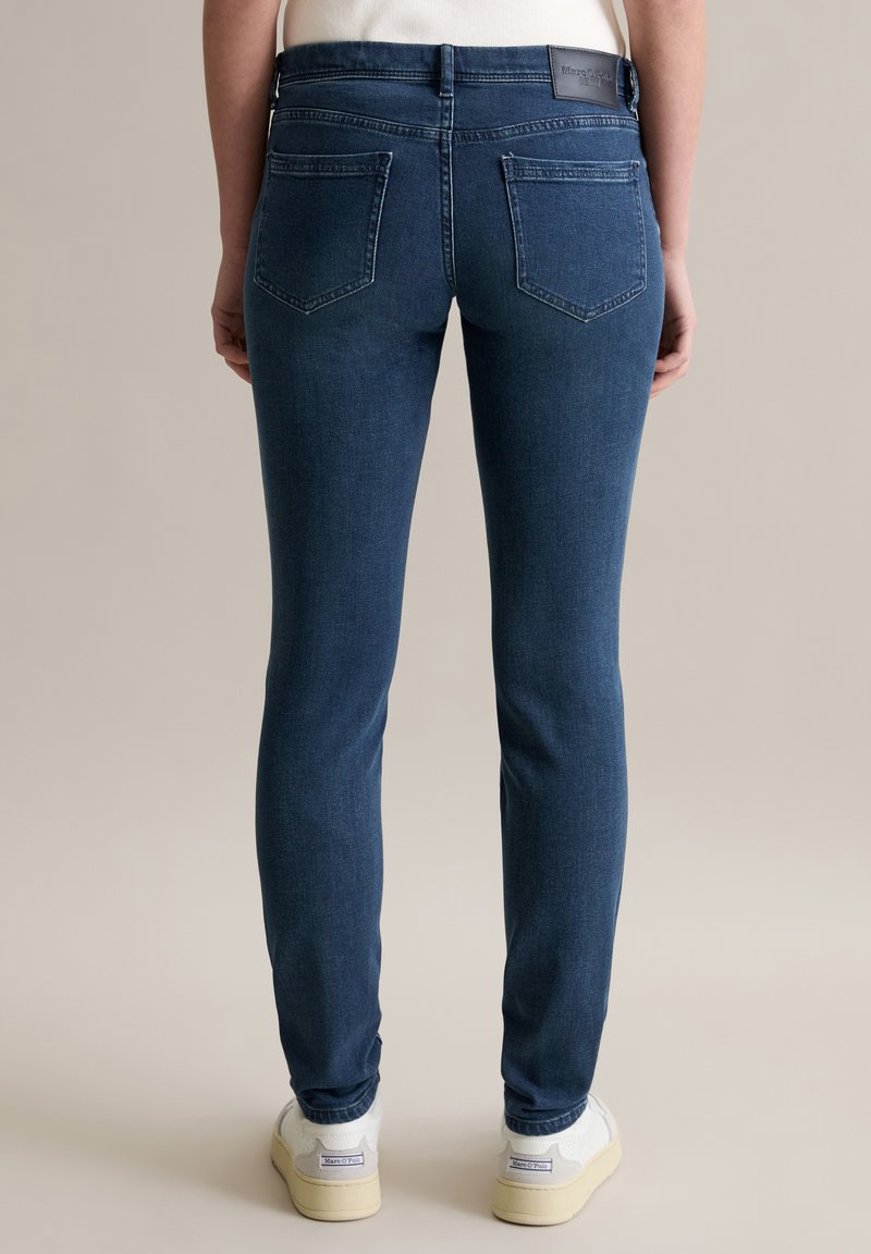 Dunkelblaue Skinny Jeans aus Denim mit einem Fünf-Taschen-Design, mittelhohem Bund und glatter Oberfläche. Besitzt ein Markenlabel auf der Rückseite.