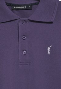 Paars polo shirt van een gestructureerde stof, met twee knopen en een klein wit logo van een golfer aan de linkerkant. Merklabel is "POLO CLUB."