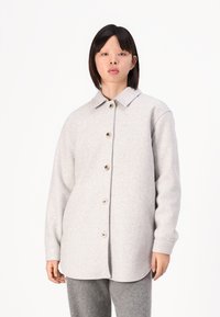 Giacca camicia in lana grigia con chiusura a bottoni, colletto arrotondato e maniche lunghe, dotata di bottoni in legno e una vestibilità morbida.