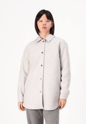 Šedá vlněná košile s kabátovým stylem, s knoflíkovým zapínáním vpředu, zaobleným límcem a dlouhými rukávy, vybavena dřevěnými knoflíky a uvolněným střihem.