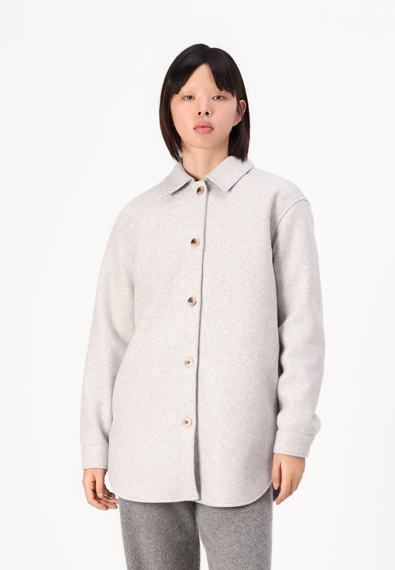 Giacca camicia in lana grigia con chiusura a bottoni, colletto arrotondato e maniche lunghe, dotata di bottoni in legno e una vestibilità morbida.