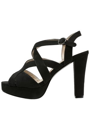 Sort ruskind høje hæle sandaler med krydsede remme og en ankelspænde. Har en plateau sål og en tekstureret overdel.