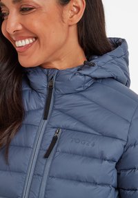 Blue puffer jacket with a hood, featuring quilted texture, zippered pockets, and a tonal logo. Front-zip closure and black hardware accents.