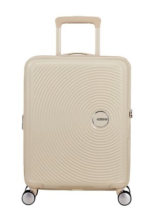 Valigia rigida beige con manico telescopico, quattro ruote girevoli e motivo a cerchi concentrici con logo American Tourister.