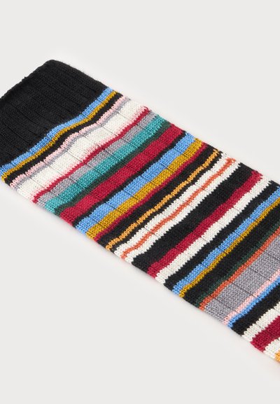Chaussette tricotée avec des rayures horizontales colorées en noir, blanc, rouge, bleu, jaune, vert, rose et gris avec un bord-côte noir.