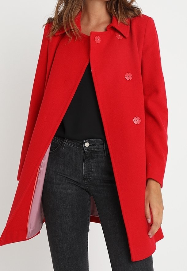 Abrigo de lana rojo con diseño de doble botonadura, que cuenta con cinco botones redondos, cuello con muesca y un forro interior suave. Combinado con jeans negros.