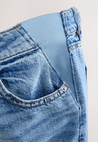 Világoskék farmernadrág puha, rugalmas derékpánttal. Elöl zsebbel és látható varrási részletekkel. Texturált anyagú kivitel.