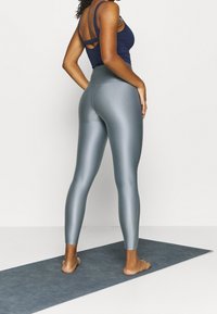 Legginsy w kolorze metalicznego turquoise z wysokim stanem, wykonane z elastycznego materiału, charakteryzujące się gładką fakturą i dopasowanym fasonem.