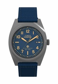 Timex Expedition-klocka med grått hölje, blå urtavla och beige timmarkörer. Den har ett marinblått texturerat armband och vattentålighet upp till 50 m.