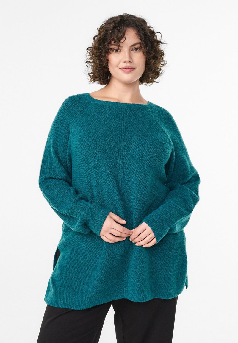 Teal knit sweater with a loose fit, wide neckline, and long sleeves. Features ribbed texture and side slits at the hem.