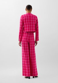 Pink plaid crop blazer and wide-leg trousers made of textured fabric. Features a checkered pattern with contrasting white lines.