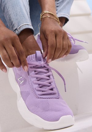 Purple athletic shoes featuring mesh material, textured pattern, round toe, thick white sole, and shoelaces with a loop for secure fitting.