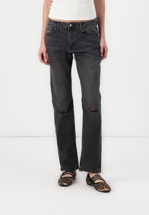 Dark gray denim jeans with a straight-leg fit, featuring two front pockets, visible stitching, and knee rips, paired with animal print flats.