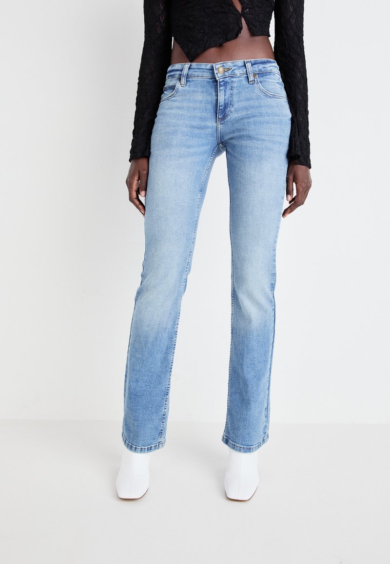 Lichtblauwe rechte spijkerbroek van denim, met een klassiek vijf-pocket ontwerp en een knoopsluiting aan de voorkant. Draag het met witte enkellaarsjes.