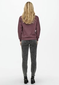 Felpa color violaceo con maniche lunghe e polsini a costine, abbinata a jeans skinny neri slavati e stivali neri con plateau chunky.