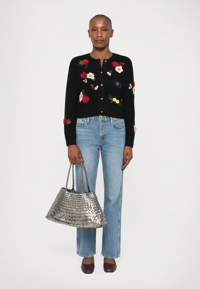 Svart stickad cardigan med färgglad blommönstring, guldbjällor, ljusblå raka jeans, metallisk silvervävd handväska och vinröda skor.