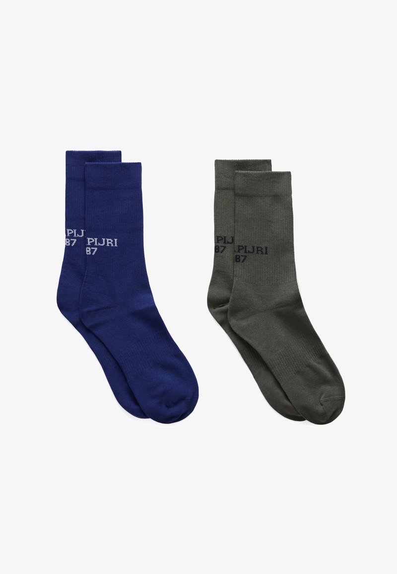 Deux paires de chaussettes montantes, une bleu marine et une gris foncé, chacune arborant le texte "PIJRI 87" près du bord-côte sur un fond blanc.