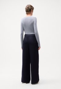 Top ajustado de manga longa cinza claro com textura canelada, combinado com calças largas de tom azul marinho escuro, com acabamento suave e cintura elástica.