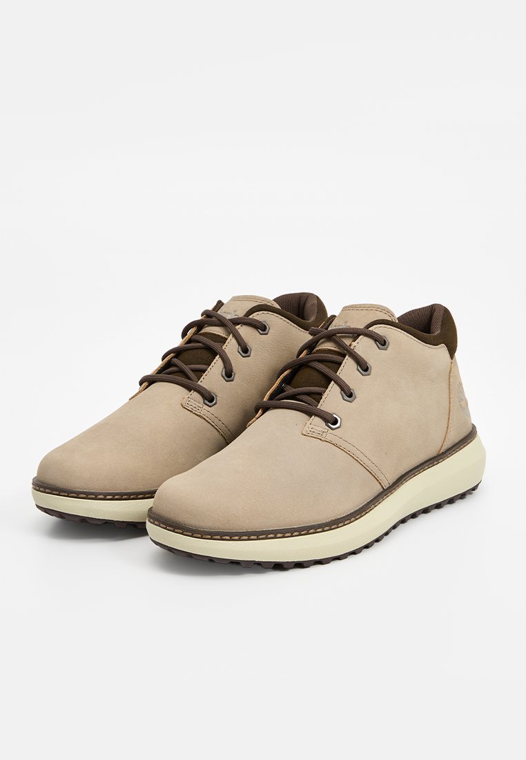 Zapatos de cuero beige con diseño de corte bajo, cordones marrones y suela de color claro. Parte superior texturizada con detalles de costura y puntera redondeada.