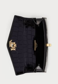 Czarna torebka z lakierowanej skóry z teksturą krokodylej skóry, z goldowym zapięciem i gładkim wnętrzem. Otwarty widok ukazuje przegródki.