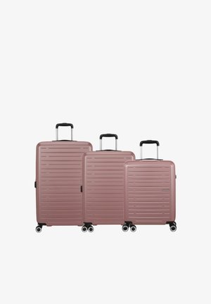 Tre valigie rigide color oro rosa con scanalature orizzontali, maniglie nere e quattro ruote, disposte dalla più grande alla più piccola.