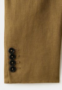 Manche en tissu tissé marron avec quatre boutons noirs cousus près du poignet, affichée à plat sur un fond blanc.