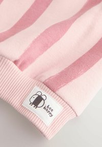 Lyserød stribet sweatshirt med ribbet kant. Har et lille vævet mærke, der viser en bi og teksten "bee happy". Blødt stof i en behagelig tekstur.