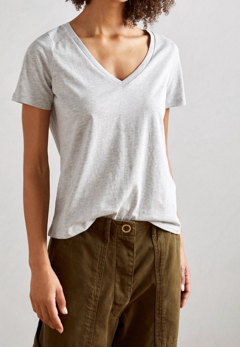 Grijs T-shirt met korte mouwen en V-hals, gemaakt van zacht stof, met een ontspannen pasvorm en een gladde textuur, gecombineerd met olijfgroene broek.