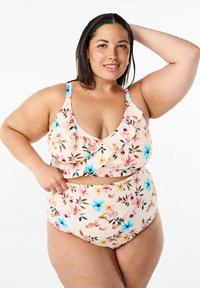 Blomsterbikiniset med en ljus persikofärgad bakgrund, volangtop med djup halsringning och högmidjade underdelar, dekorerad med rosa och blå blommor.