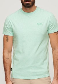 T-shirt a maniche corte color verde menta, realizzato in un morbido tessuto testurizzato, con scollo rotondo e un piccolo logo ricamato sul petto.