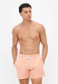 Shorts de bain rose clair avec taille à cordon, poches latérales et un petit logo. Fabriqués en tissu lisse et à séchage rapide.