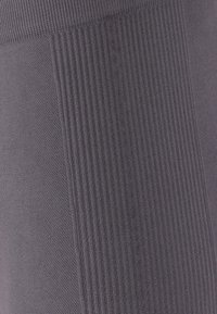 Stretch-farkat legginsit tummanharmaana, joissa on ribbitetty pinta yhdellä puolella ja sileä pinta toisella, tarjoten vastakkaisia muotoiluja.